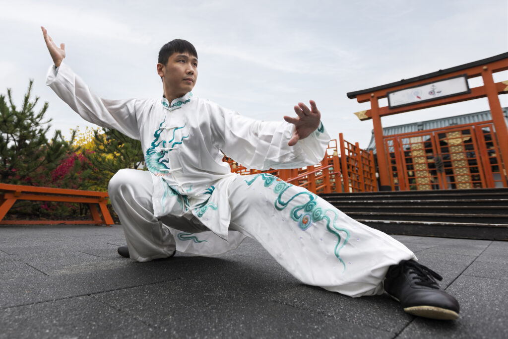 full shot man practicing tai chi outdoors